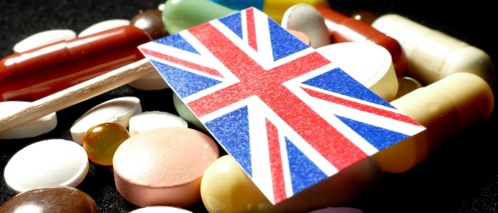 United Kingdom flag with lots of medical pills isolated on black background, symbolizing the UK’s pilot schemes to speed patient access to new medicines