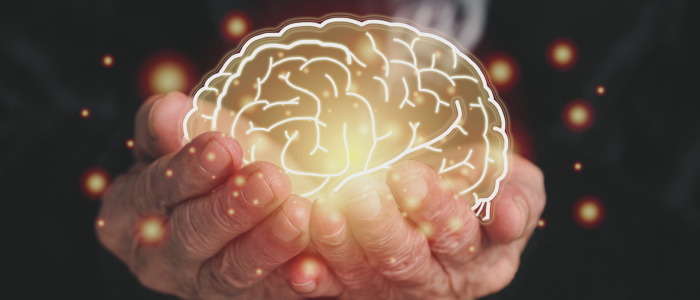 Elderly hands hold glowing brain illustration.