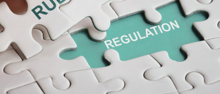 Close-up of white puzzle pieces with one missing piece revealing the word “REGULATION” on a green background.