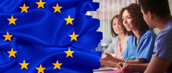 EU flag beside group of healthcare professionals discussing at a table.