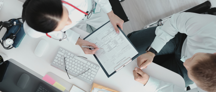 Two doctors reviewing medical forms together at a desk, viewed from above. To represent that OneMedNet teams up with Datavant to deliver AI-powered, tokenized real-world data.