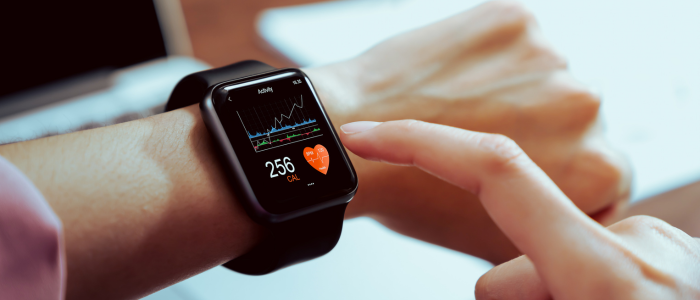 Person taps a smartwatch displaying heart rate and health data charts, showing digital health monitoring.
