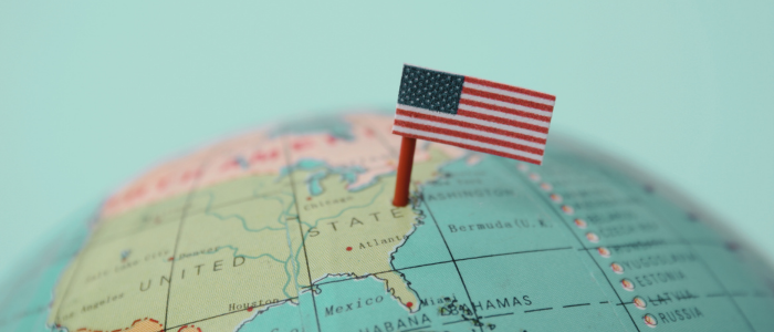 Miniature U.S. flag pinned into a globe map showing the United States.