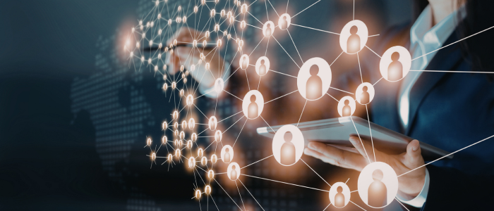 Person holding a tablet with glowing connected user icons forming a network overlay across the foreground.