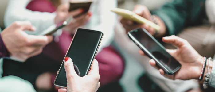 Close-up of multiple hands holding smartphones, typing or scrolling, in a social setting, reflecting access to electronic health records 