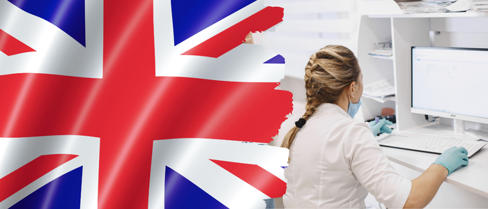 UK flag beside healthcare worker using desktop computer in clinical setting.