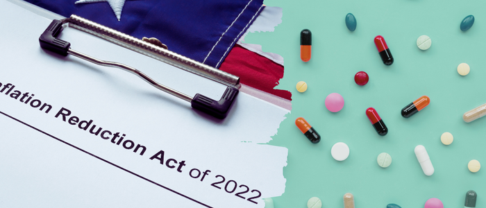 Clipboard with Inflation Reduction Act of 2022 document over USA flag beside scattered pills and capsules.