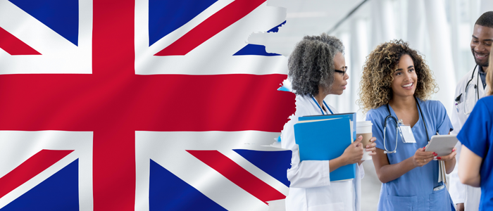 UK flag beside group of smiling healthcare professionals discussing information on a tablet.