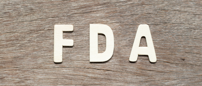 FDA logo on a wood-textured background, accompanying an article about the agency’s reorganization into dedicated AI and real-world evidence analytics divisions