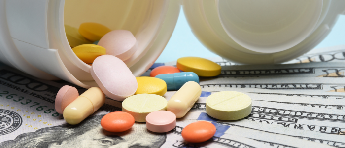 Assorted prescription pills spilling from pill bottles onto US dollar banknotes, illustrating drug pricing and healthcare costs.