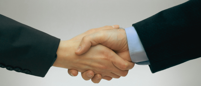 Two people in business attire shaking hands, symbolizing an agreement or partnership