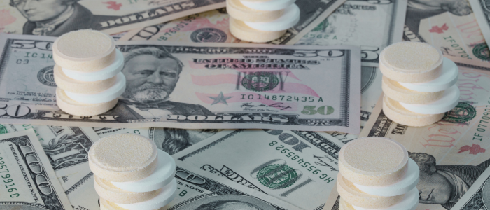Stacks of white pills rest on scattered US dollar bills. To represent that a study reveals the Inflation Reduction Act's 