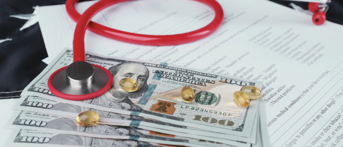 Red stethoscope resting on hundred-dollar bills and scattered yellow capsules atop medical documents. To represent that Trump executive order overturns innovative Medicare and Medicaid drug pricing models.