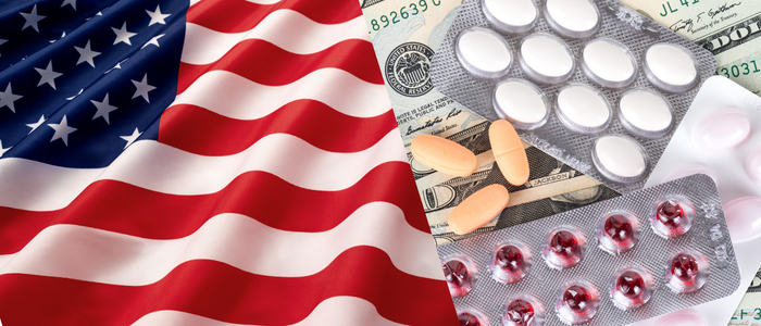 US flag beside prescription pills and blister packs scattered over dollar bills, illustrating U.S. drug pricing.