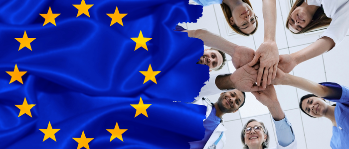 EU flag beside group of healthcare professionals stacking hands in teamwork gesture.