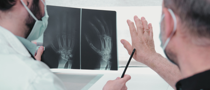 Doctor reviews hand X-rays with patient pointing to affected area.